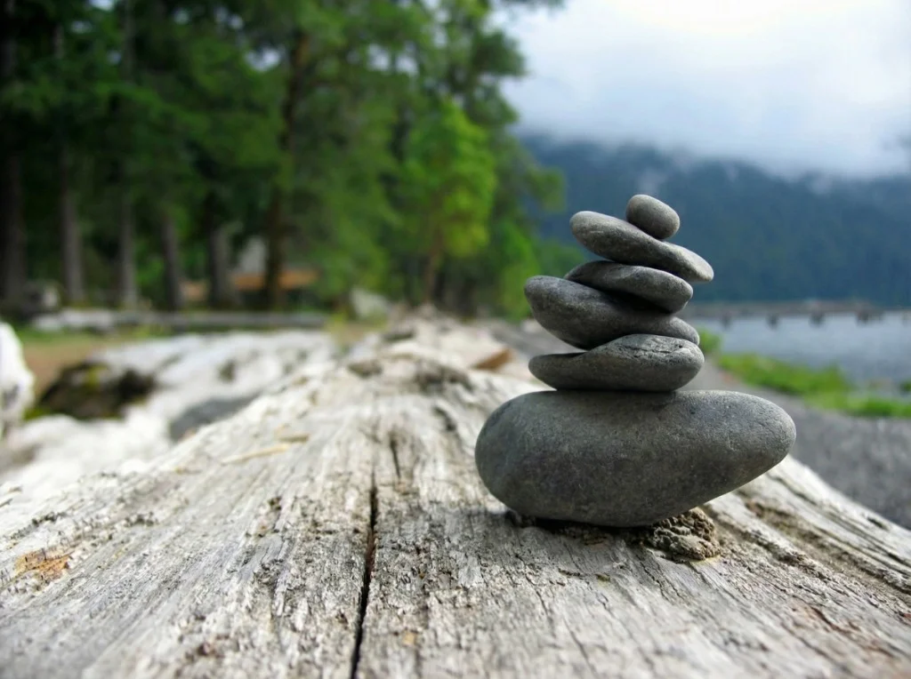 Balanced zen stones along a sunlit riverbank